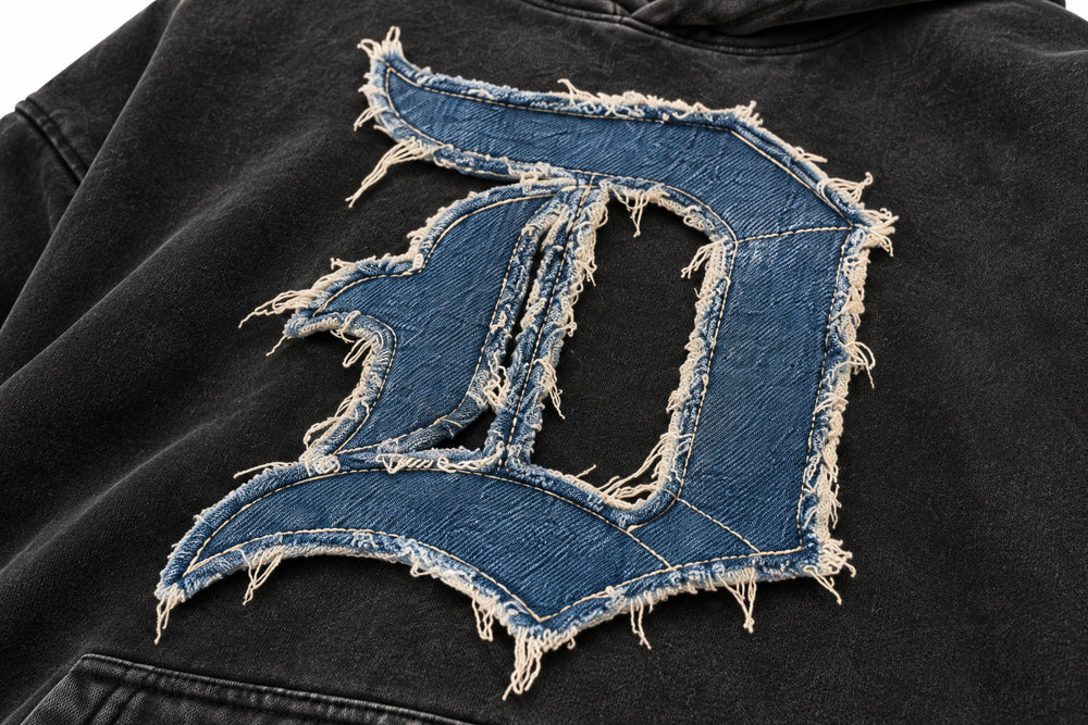 Close-up of the denim appliqué decoration on the Denim Letter washed black denim appliqué oversized hoodie