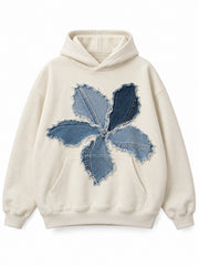 Front view of the Denim Petals cream denim appliqué oversized hoodie with a large flower assembled from blue denim appliqué petals