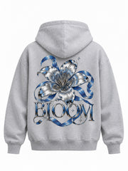 Back view of the Chrome Bloom ash gray DTF print boxy hoodie with chrome-effect flower with a blue ribbon and bold BLOOM lettering