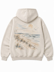 Back view of the Coastal Study light stone DTG print hoodie with an illustrated shore with dune grasses, sea and birds