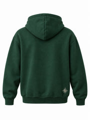 Back view of the Alpine Crest forest green embroidered hoodie with small ivory compass embroidered near the lower right hem
