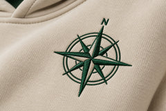Close-up of the embroidered decoration on the Trail Compass warm sand embroidered hoodie