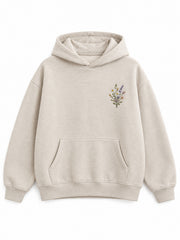 Front view of the Wild Meadow oatmeal embroidered hoodie with a small multicolor wildflower sprig at the left chest