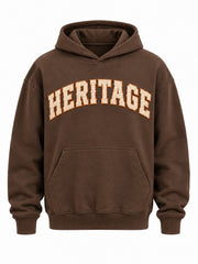 Front view of the Heritage Stitch brown felt appliqué hoodie with cream HERITAGE curved felt letters with orange blanket stitching