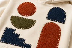 Close-up of the patchwork appliqué decoration on the Patchwork Studio cream patchwork appliqué boxy hoodie