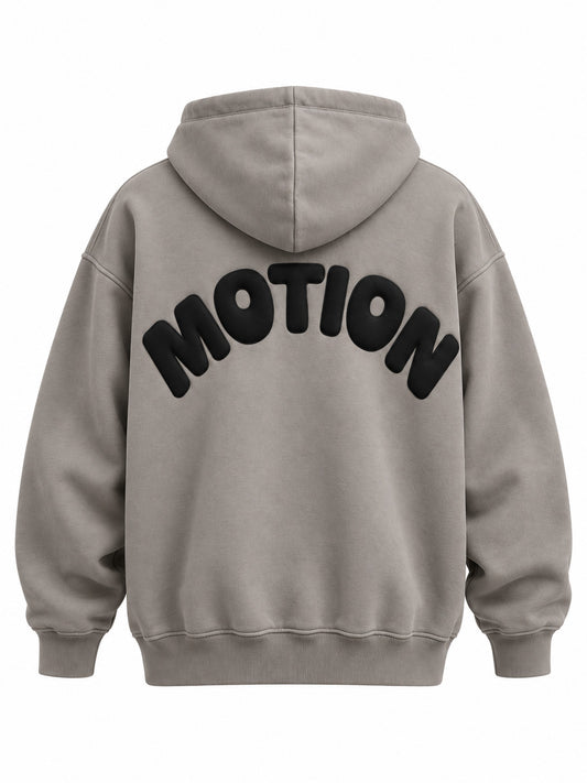 Back view of the Slow Motion warm gray puff print oversized hoodie with large black MOTION lettering curved into a semicircle in puff print