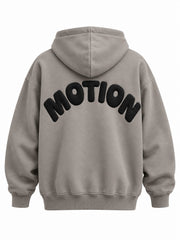 Back view of the Slow Motion warm gray puff print oversized hoodie with large black MOTION lettering curved into a semicircle in puff print