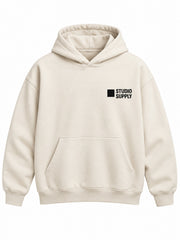 Front view of the Studio Supply ecru screen print boxy hoodie with black STUDIO SUPPLY lettering with a small square icon on the left chest