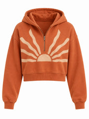 Front view of the Solar Trace burnt orange sun faded cropped half-zip hoodie with large cream sunburst graphic across the chest and half-zip placket